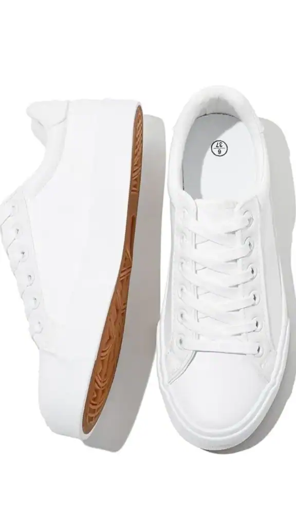 The image features a pair of white casual sneakers with a minimalist design, showcasing a smooth, seamless upper material. The shoes feature traditional lace-up detailing and a platform sole with a textured gum rubber bottom, providing both style and comfort for everyday wear. These versatile sneakers have a relaxed fit, making them suitable for various fall outfits.