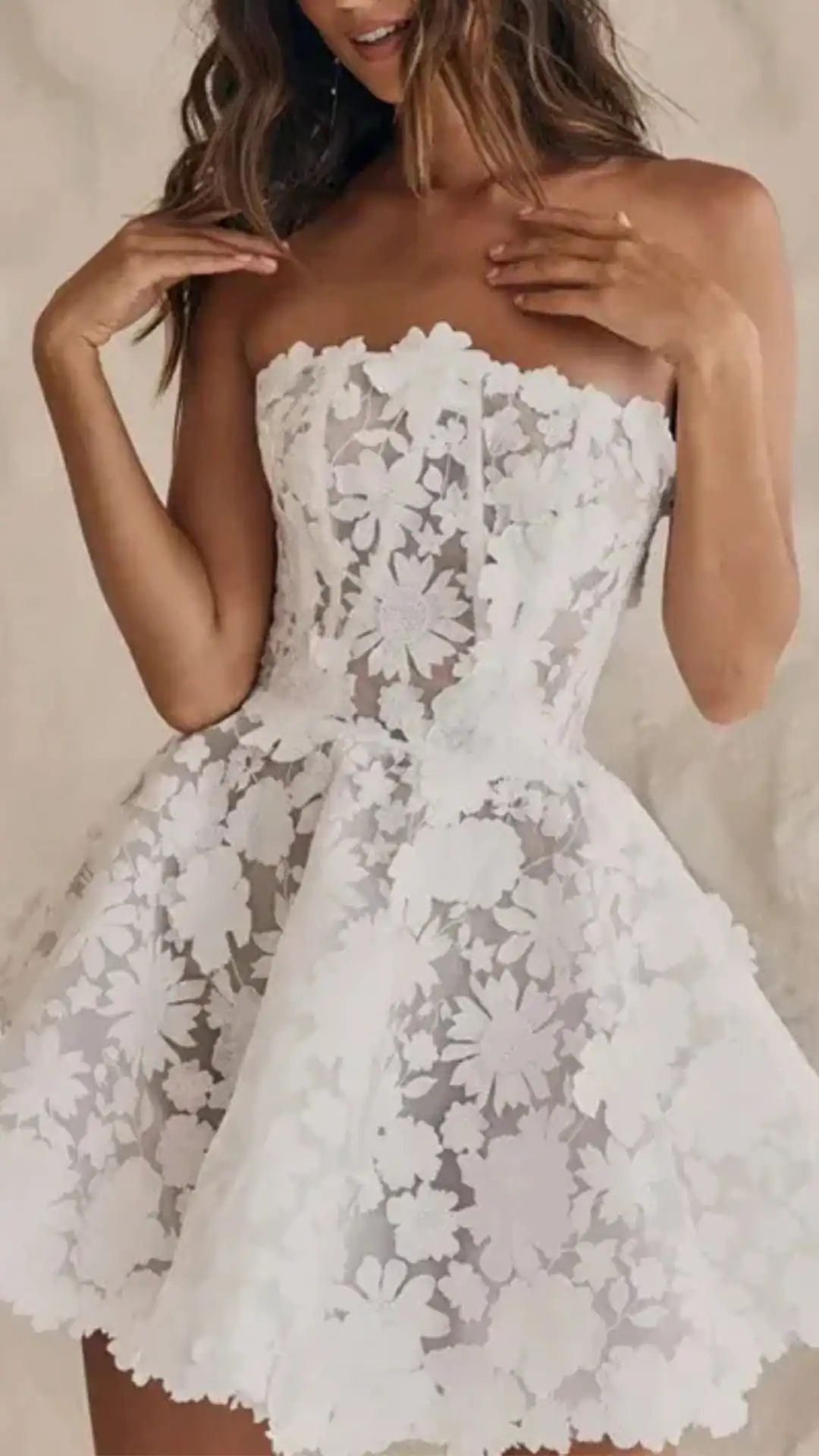 This white homecoming dress features a strapless design crafted from a delicate, textured lace overlay adorned with intricate floral patterns, creating a romantic and ethereal vibe. The fitted bodice flows into a voluminous skirt, making it a perfect choice for formal events, parties, or school dances, catering to teenage girls seeking a cute and trendy look.