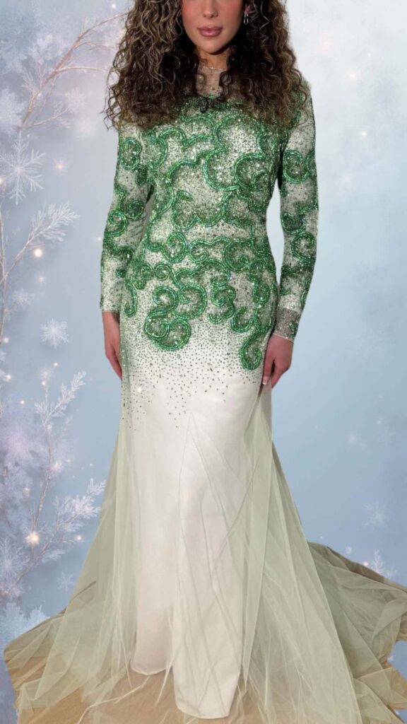 This elegant winter formal dress features a full-length silhouette with a fitted bodice adorned in intricate green and silver beadwork, showcasing a sophisticated round neckline and long sleeves. The dress includes a flowing white skirt with a sheer overlay, offering a graceful drape, while delicate accents of shimmering sequins embellish the lower hem, enhancing its classy appeal. Perfect for chilly evenings, this outfit combines warmth and style effortlessly.