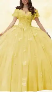 The dress features a vibrant yellow hue with a voluminous ball gown silhouette. It has a sweetheart neckline, off-the-shoulder short sleeves, and is adorned with delicate butterfly embellishments and shimmering sequins that enhance its elegance. The floor-length skirt is layered with soft tulle, offering a romantic and whimsical appearance.