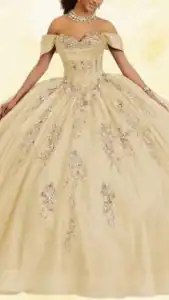 This yellow quinceañera dress features an elegant off-the-shoulder neckline and a fitted bodice adorned with sparkling embellishments. The voluminous skirt cascades to the floor, showcasing intricate floral embroidery with silver accents that create a luxurious effect. The soft, shimmering fabric enhances its fairy-tale quality, making it a stunning choice for a memorable celebration.