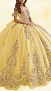 This stunning yellow Quinceañera dress features an off-the-shoulder neckline and a fitted bodice adorned with intricate silver beadwork and sequins. The voluminous, floor-length skirt showcases lavish embroidery with elegant patterns cascading down, creating a regal silhouette. The soft yellow hue is complemented by shimmering silver details, making it a striking choice for a celebratory occasion.