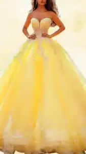 The dress features a strapless sweetheart neckline and a fitted bodice adorned with intricate silver embroidery, leading into a voluminous, floor-length skirt made of soft tulle in a bright, sunny yellow. The skirt is beautifully embellished with delicate white floral appliqués near the hemline, creating a striking contrast against the vibrant yellow fabric. This Quinceanera dress combines elegance and playful charm, perfect for a memorable celebration.